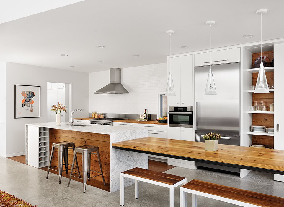 lichte moderne keuken met kookeiland van marmer en tafel in het verlengde