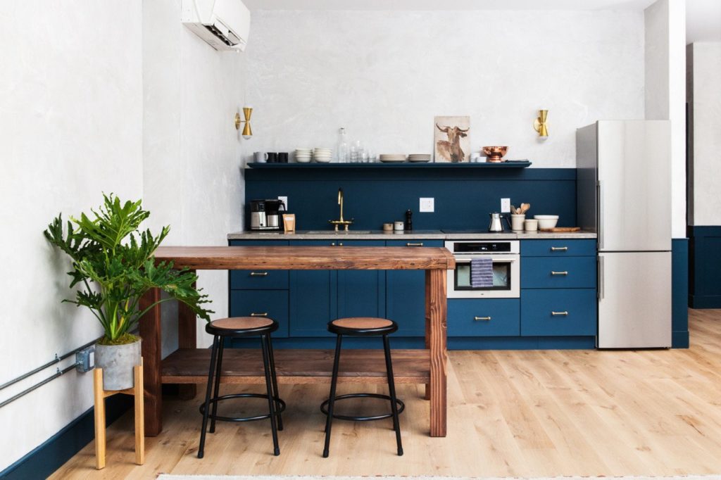 blauwe keukenkastjes en houten bartafel