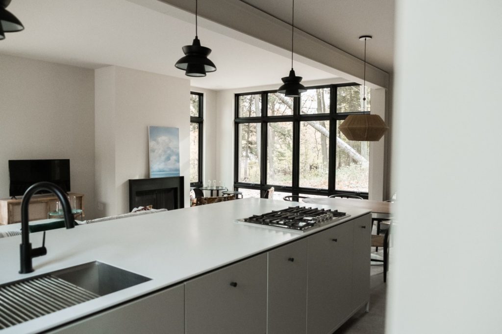 grijze keukenkastjes met wit hoogglans aanrechtblas met gasfornuis