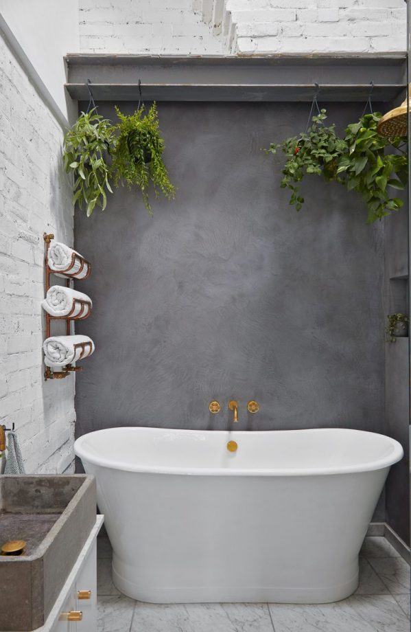 betonlook badkamer muur met wit vrijstaand bad
