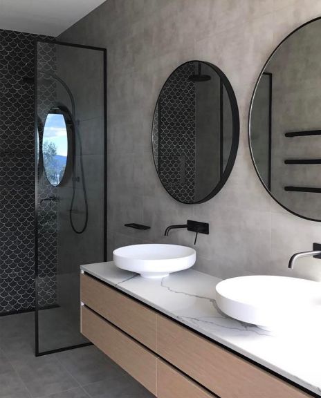 moderne betonlook badkamer met zwevend badkamermeubel, ronde spiegels en marmeren wastafelblad