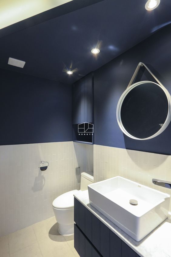 modern blauw toilet met witte onderwand en ronde spiegel