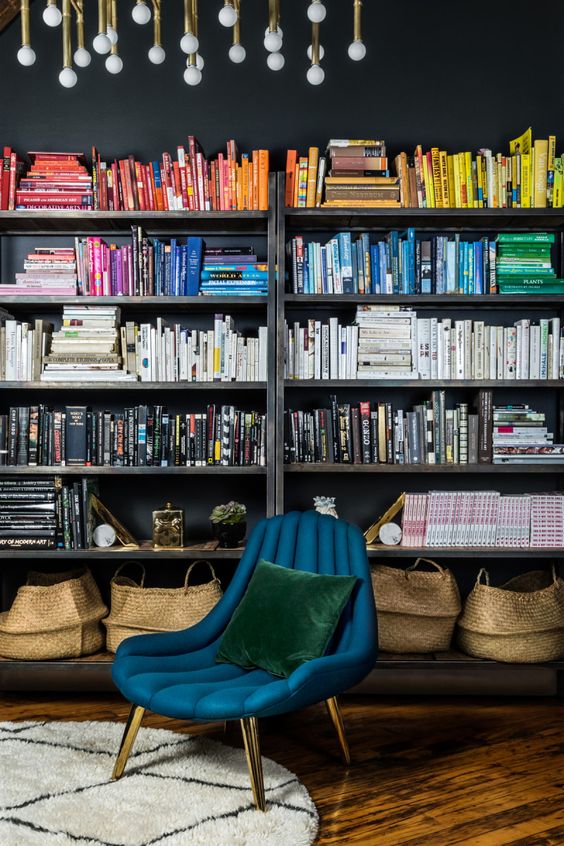 boekenkast idee in klassieke woning met stoel voor kast met boeken gesorteerd op kleur